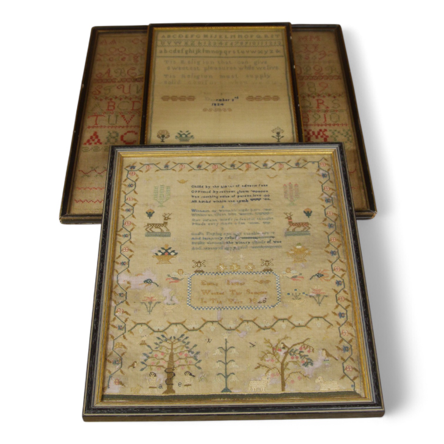 Three framed early to mid 19th century samplers, including an 1828 Adam and Eve sampler embroidered by Emma Parker, worked with a floral border with various spot motifs and verse, together with an alphabet sampler by Jan